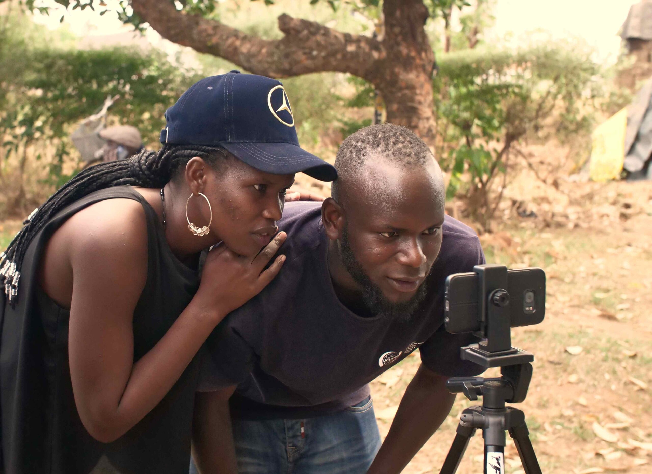 A man and a woman staring into a smart phone camera, which is mounted on a tripod