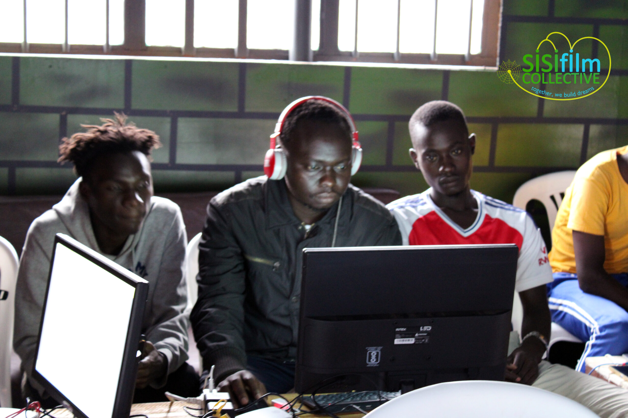 Three African boys are seated Infront of a laptop